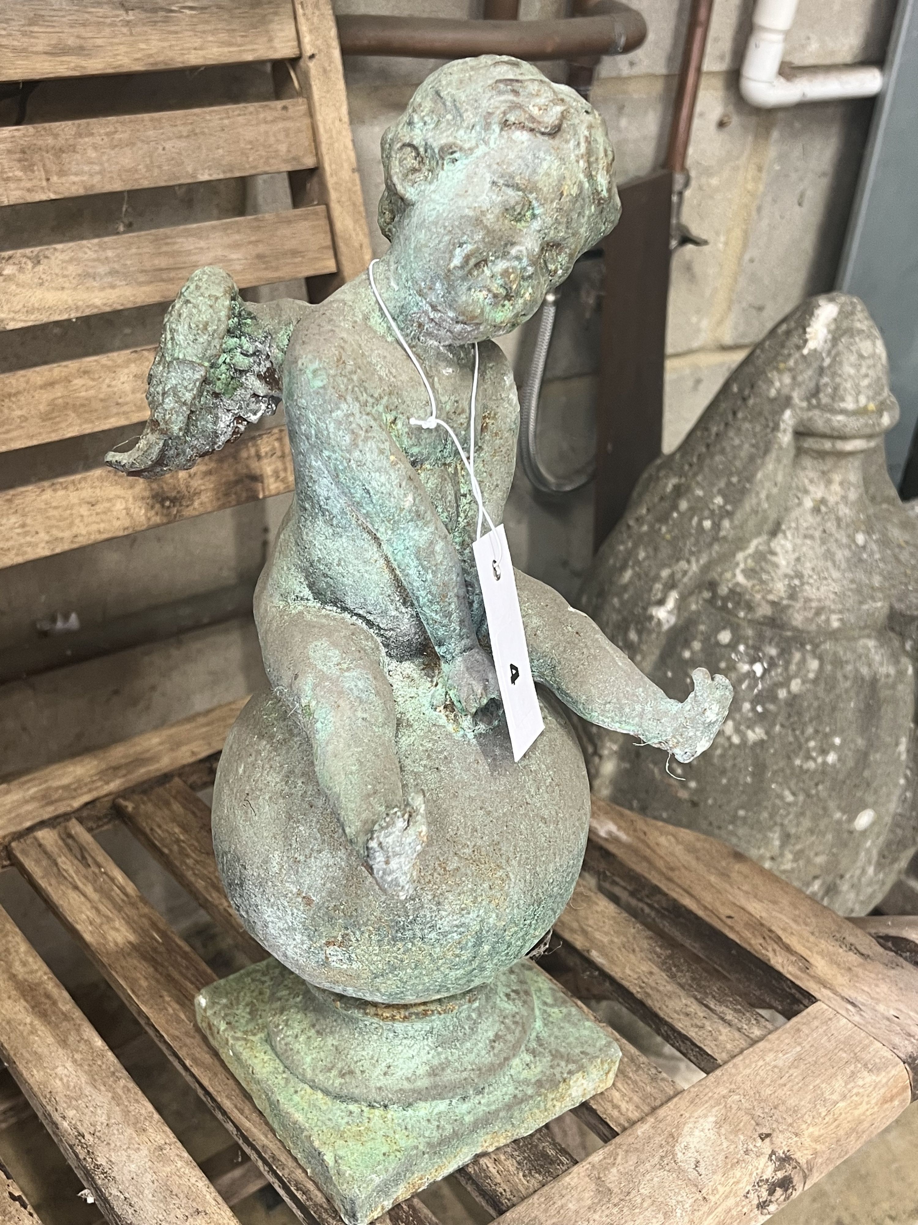 A cast iron cherub and orb garden ornament, height 38cm
